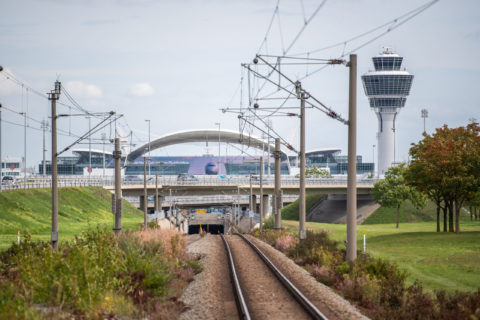 Leere Gleise führen zum Flughafen München mit dem Tower im Hintergrund.