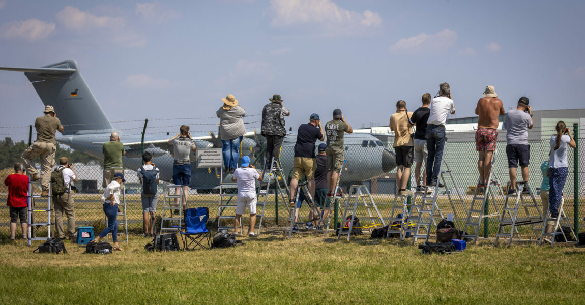Air Defender 2023 lockt Planespotter an: Sie stehen an einem Zaun vor dem Fliegerhorst Wunstorf und fotografieren einen Airbus A400M der Luftwaffe.