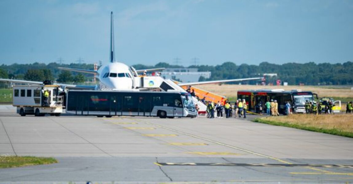 Passagiere verlassen das auf dem Flugfeld abgestellte Flugzeug und steigen in bereitgestellte Busse.