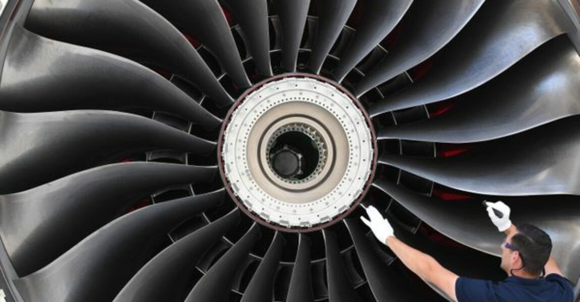 Ein Flugzeugtriebwerk vom Typ Rolls-Royce Trent XWB wird von einem Arbeiter in einer Montagehalle bei Rolls-Royce im brandenburgischen Dahlewitz begutachtet.