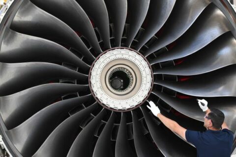 Ein Flugzeugtriebwerk vom Typ Rolls-Royce Trent XWB wird von einem Arbeiter in einer Montagehalle bei Rolls-Royce im brandenburgischen Dahlewitz begutachtet.