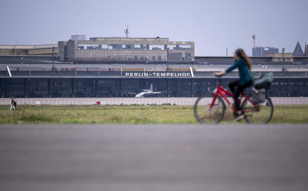 Eine Fahrradfahrerin fährt über das Rollfeld auf dem Gelände des ehemaligen Flughafens Tempelhof. 