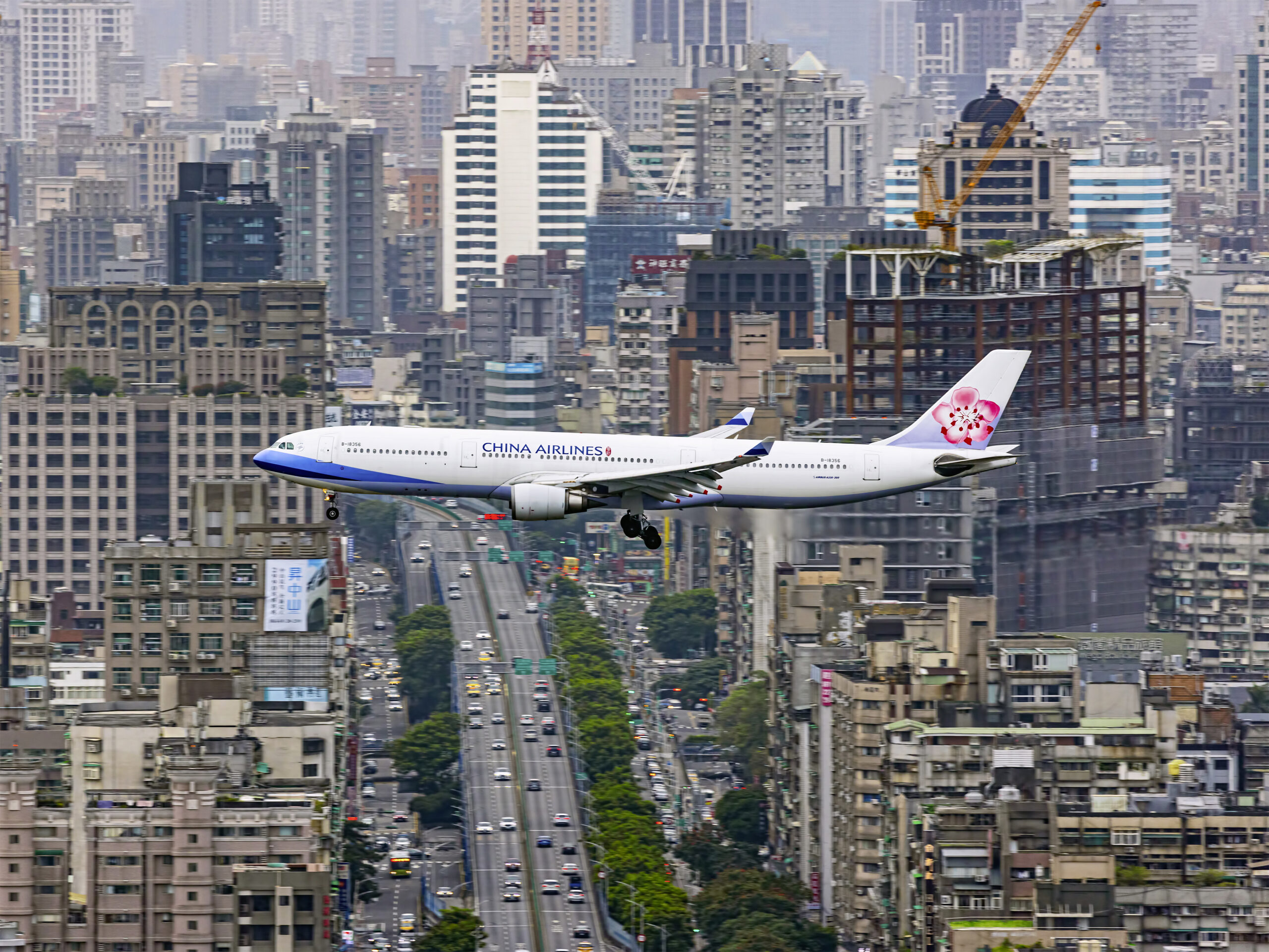 Zuweilen finden sich selbst Flugzeuge im Großstadt-Dschungel zurecht. Wie zum Beweis nimmt diese A330-300 der China Airlines, Kennung B-18356, problemlos Kurs auf ihren Heimatflughafen Taipeh. Und der italienische Fotograf Stefano Rizzi hielt den Anflug dankbar fest. Bild: Stefano Rizzi