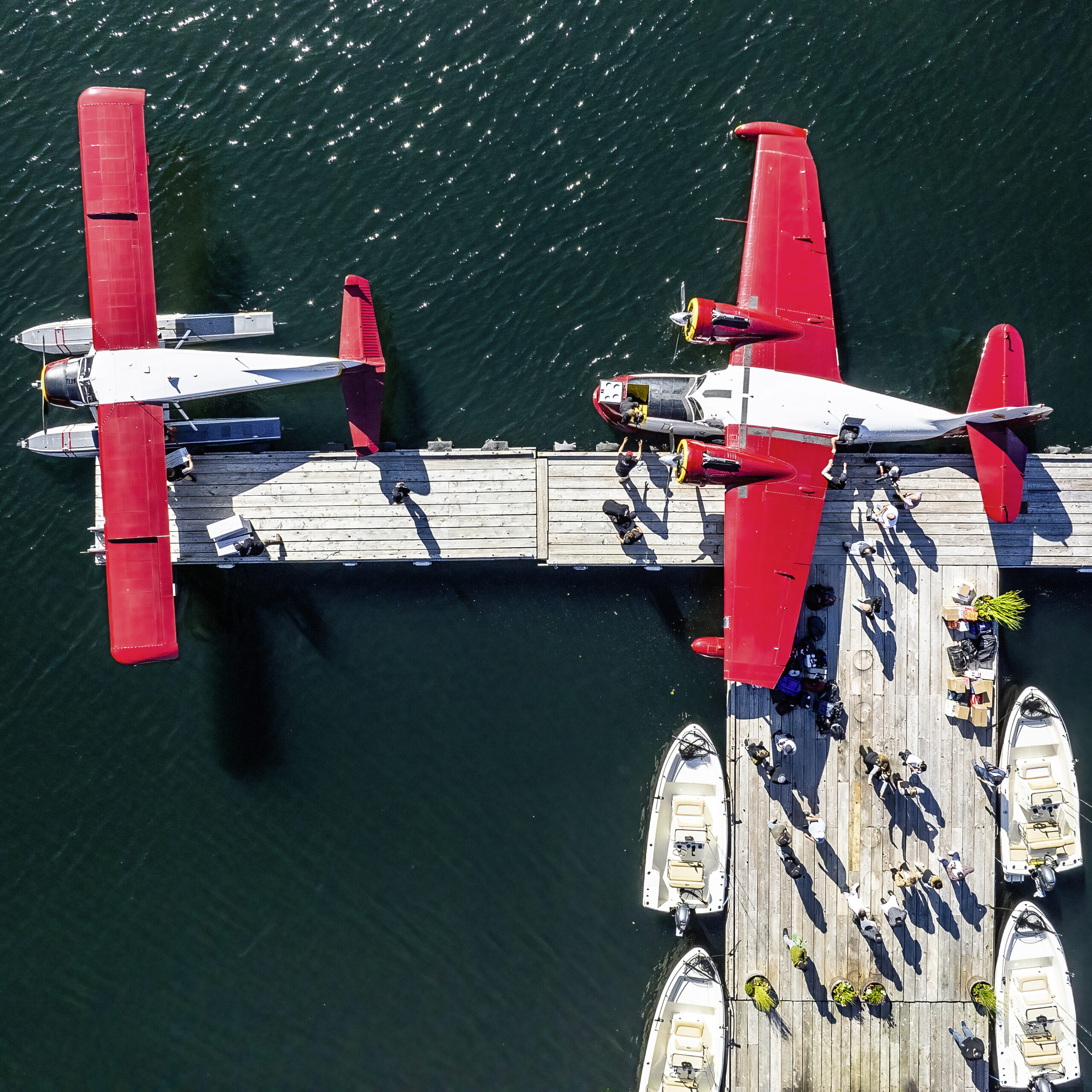 Aus der Vogelperspektive betrachtet, gleicht vieles  einer Spielzeugszenerie. Doch die 80 Jahre alte Grumman G-21A „Goose“ der Wilderness Seaplanes (rechts) ist ebenso echt wie die DHC-2, der Steg, die Boote und die Menschen. Ryan Patterson hielt das Geschehen im kanadischen Rivers Inlet, British Columbia, Mitte des Jahres fest. Bild: Ryan Patterson