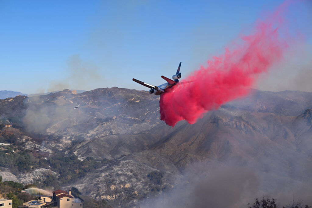 Vor dem 10 Tanker fliegt ein kleines Pfadfinderflug- zeug, das die optimale Stelle für den Abwurf des Feuerlösch- mittels markiert.
