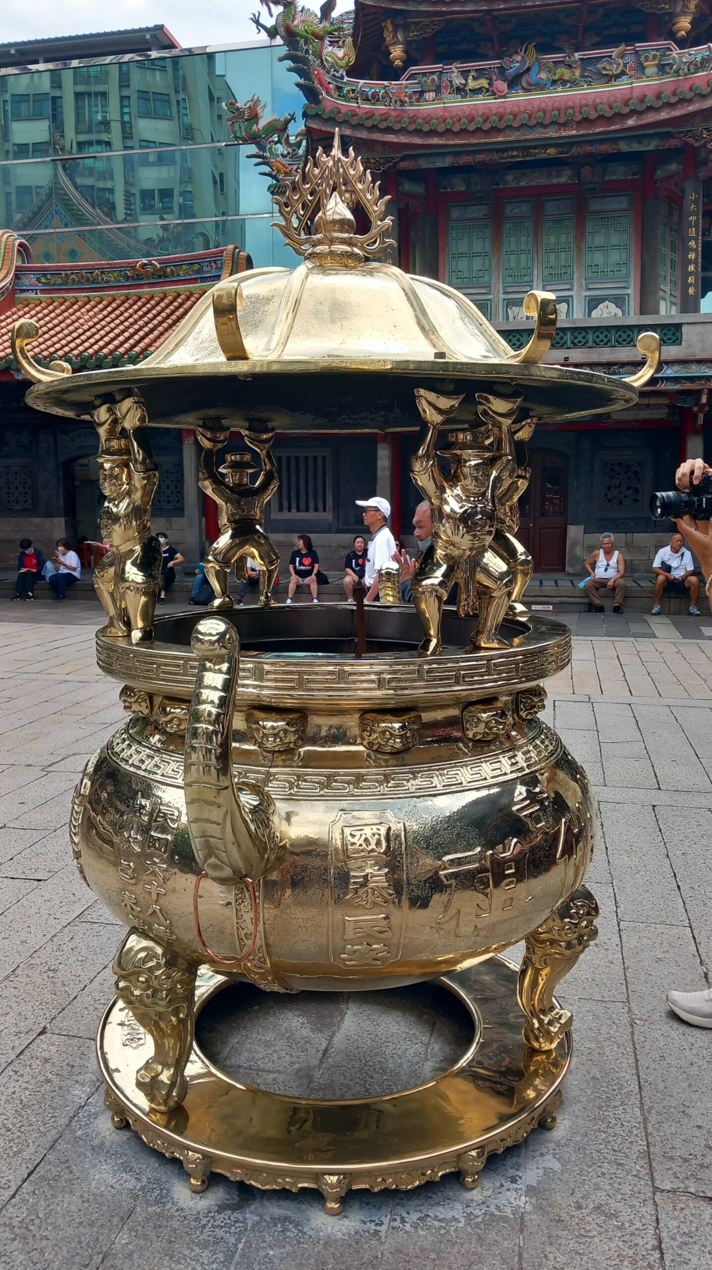 Antike Opferschale im Longshan-Tempel Taipehs. Die Figuren zeigen bei der Bevölkerung unbeliebte holländische Besatzer, die Taiwan zwischen 1624 bis 1662 kontrollierten. Zur „Strafe“ müssen sie bis heute den schweren goldenen Deckel tragen.  Bild: Wolfgang Borgmann