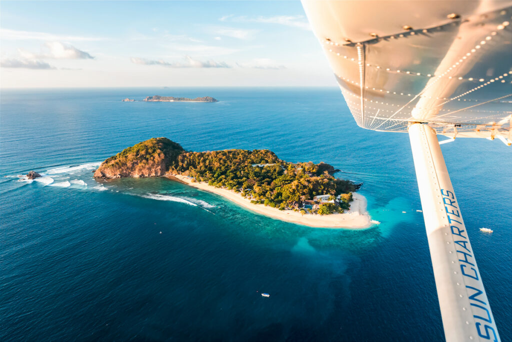 Blick aus Wasserflugzeug heraus auf Insel im Meer