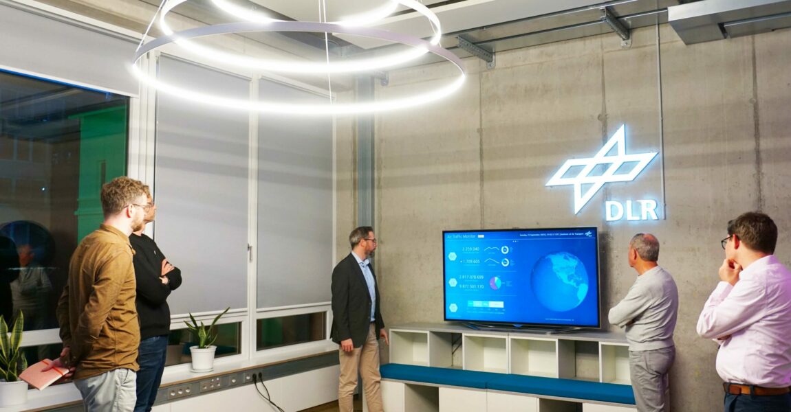 Der Luftfahrt-Presse-Club zu Gast im DLR-Institut für Luftverkehr. Im Bild zusammen mit Institutsdirektor Dr. Florian Linke (Mitte) vor einem Monitor, der die aktuellen globalen Flugbewegungen zeigt. 