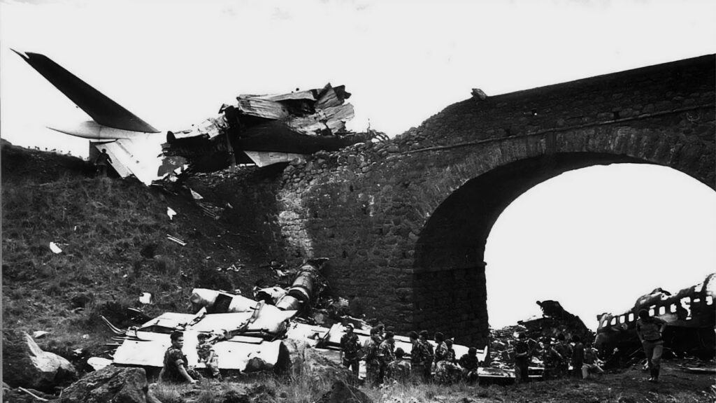 Der zerbrochene Rumpf brennt vollständig aus. Teile liegen unter und auf der Brücke.