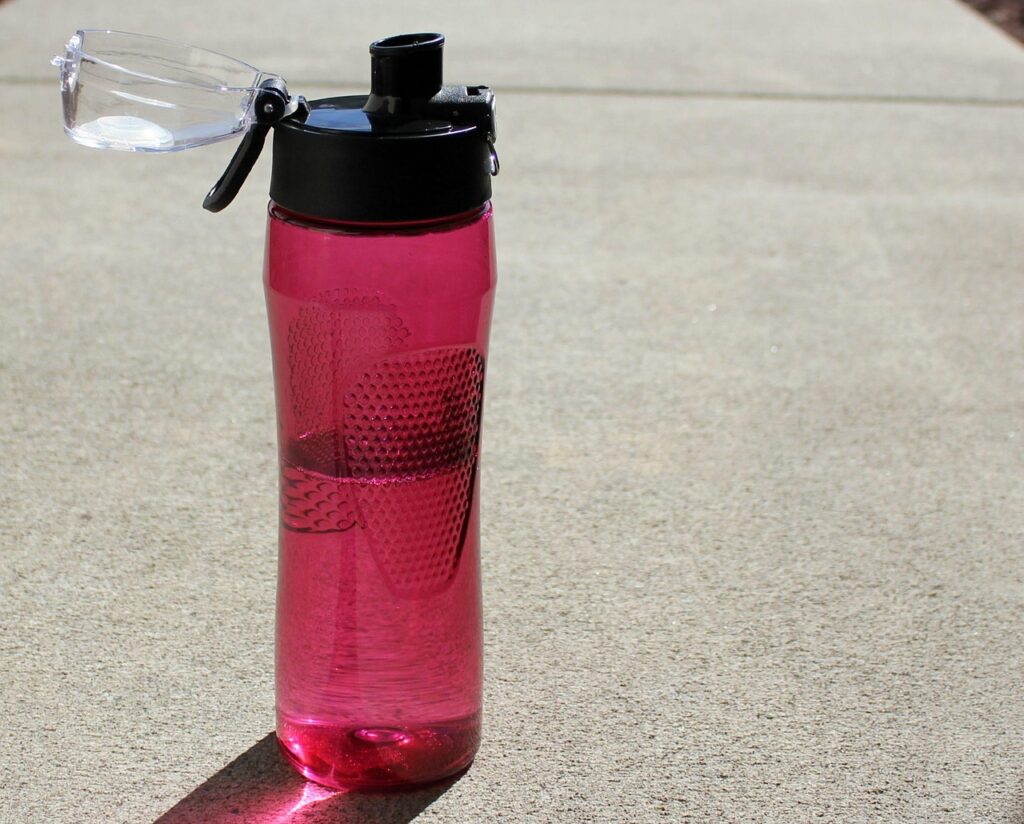 Wasserflasche in Pink mit ca. zur Hälfte Wasser drin